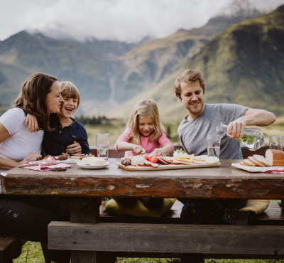 Eine glückliche Familie mit einer tollen Jausen beim Wandern. So kann ein Familienurlaub im Hotel Palace aussehen