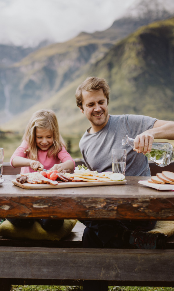 Eine glückliche Familie mit einer tollen Jausen beim Wandern. So kann ein Familienurlaub im Hotel Palace aussehen